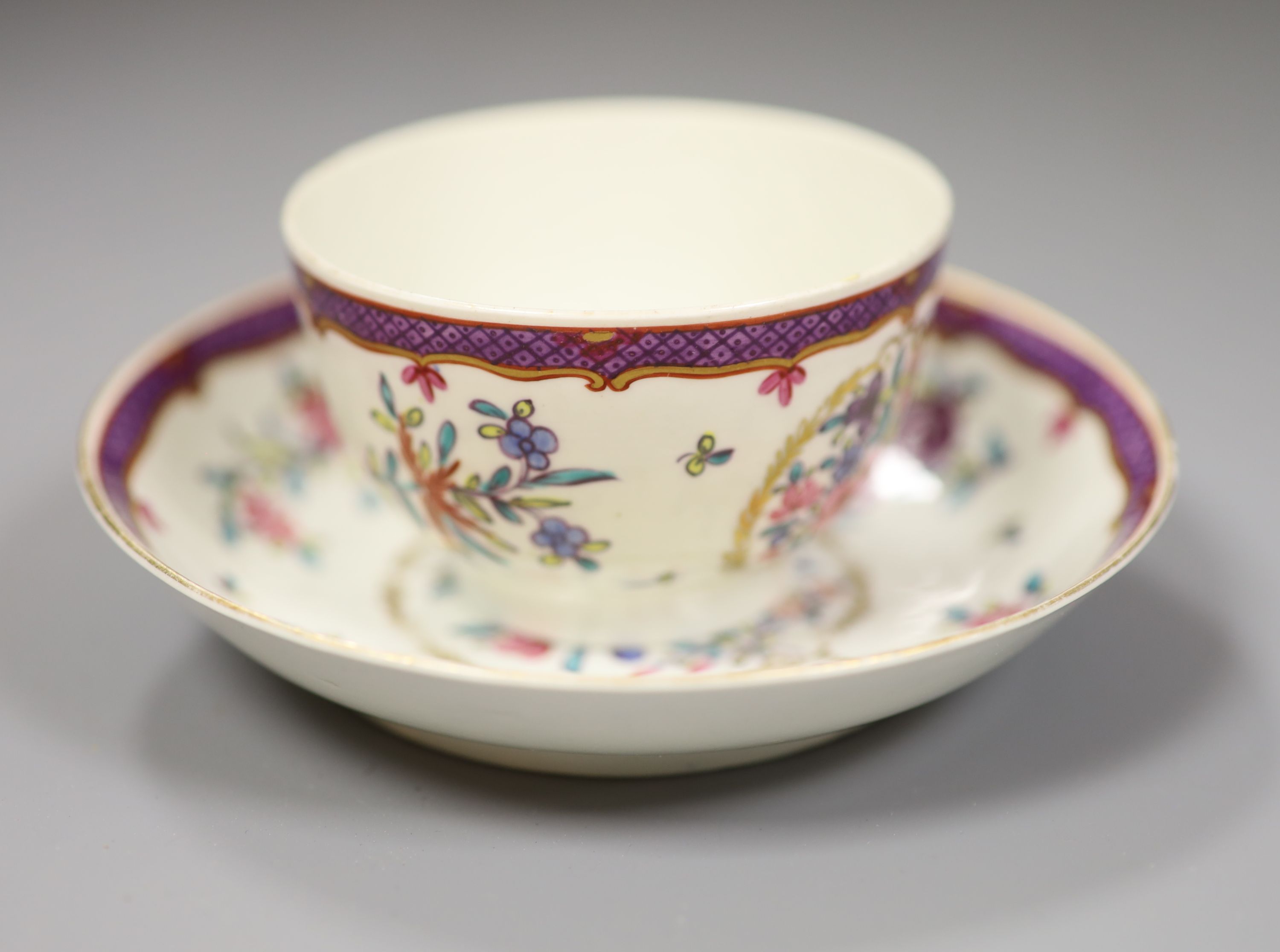 An 18th century Worcester teabowl and saucer painted Companie des Indes style with flowers in a circular gilt leaf panel